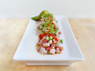 A long white plate and fish ceviche running down the middle